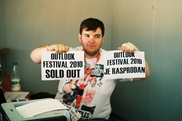 Outlook 2011 13019 An overweight man holding up two pieces of paper saying: Outlook Festival 2010 sold out