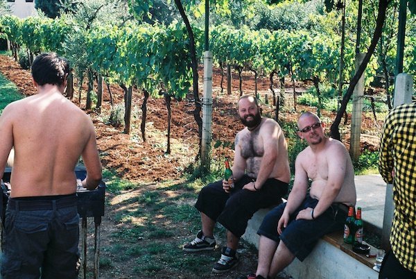 Outlook 2011 13020 2 over-weight men drinking beer next to a grape vines with another man barbecuing next to them