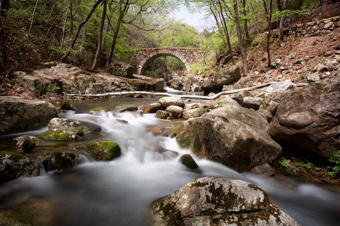 A long exposure of a river in front of a bridge