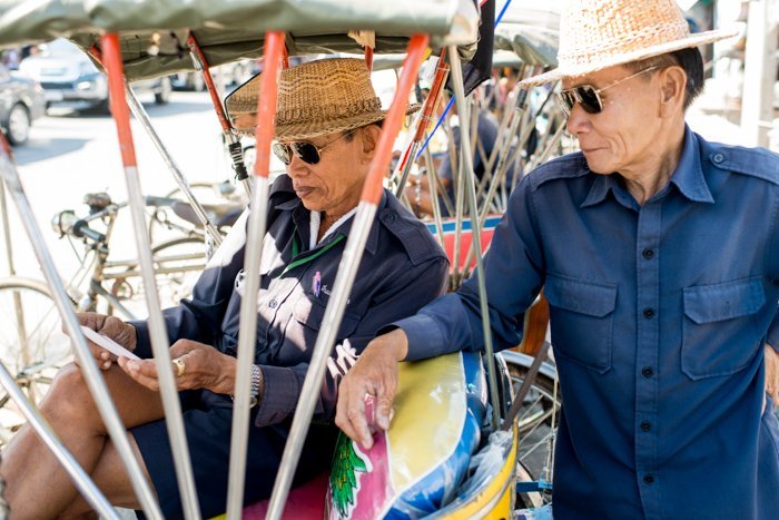 Documentary photography portrait of two men in straw hats and sunglasses in a Market in Chiang Mai, Thailand.